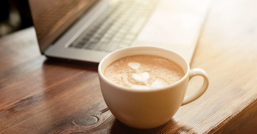 Tasse Kaffee-Cappuccino mit grauem Laptop auf Holztisch. Geschäftskonzept