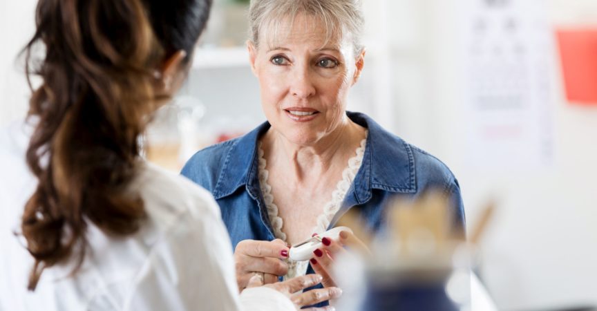 Eine besorgte ältere Frau hält ein Glaukometer, während sie mit einer Ärztin über ihre Diabetes-Diagnose spricht.