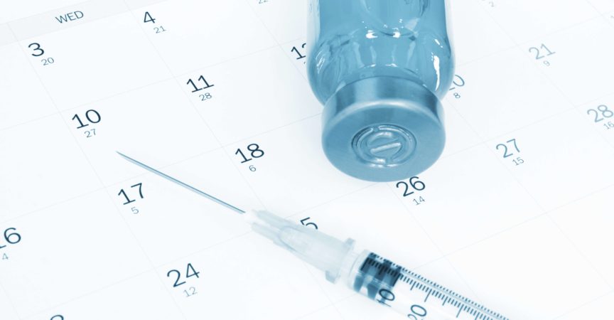 Impfstoff und Spritze auf Kalender.