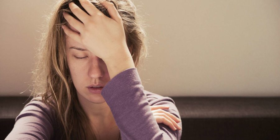 Frau, die unter Stress oder Kopfschmerzen leidet und vor Schmerzen das Gesicht verzieht