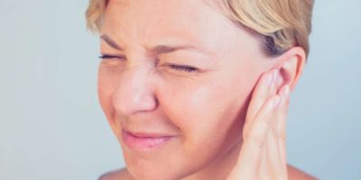 junge Frau mit Ohrenschmerzen, die ihre schmerzhaften Kopfohren berührt