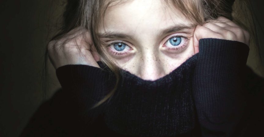 Besorgtes und verängstigtes Mädchen versteckt ihr Gesicht