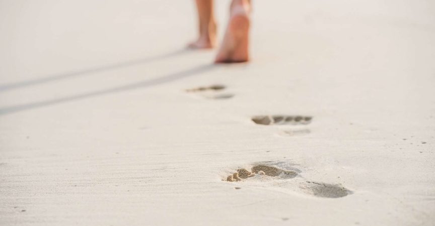 Kaukasische junge Frau, die barfuß im Sand geht, Nahaufnahme.
