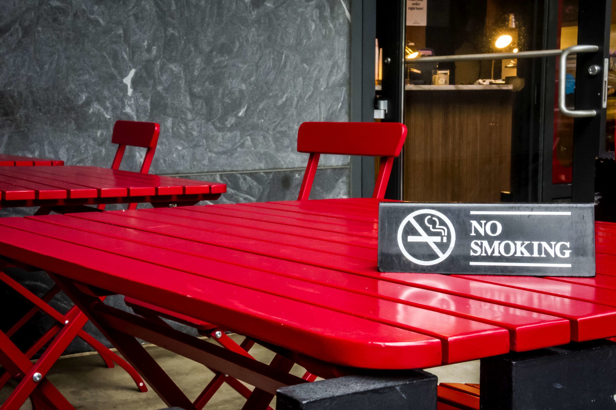 No smoking sign on a red table in a outdoor restaurant