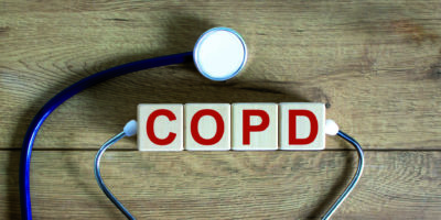COPD medizinisches Konzept. Holzwürfel mit der Aufschrift ‚COPD – chronisch obstruktive Lungenerkrankung‘, Stethoskop. Schöner hölzerner Hintergrund. Platz kopieren.