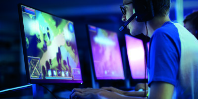 Team von professionellen eSport-Gamern, die in einem kompetitiven MMORPG/Strategie-Videospiel auf einem Cyber-Games-Turnier spielen. Sie sprechen miteinander in Mikrofone. Arena sieht cool aus mit Neonlichtern.