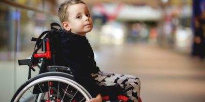 Netter kleiner Junge im Rollstuhl im Einkaufszentrum