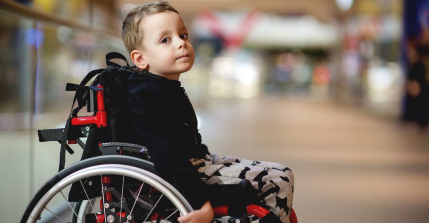 Netter kleiner Junge im Rollstuhl im Einkaufszentrum