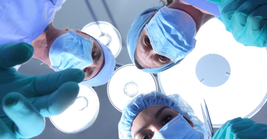 Gruppe von Chirurgen, die auf den Patienten herabblicken
