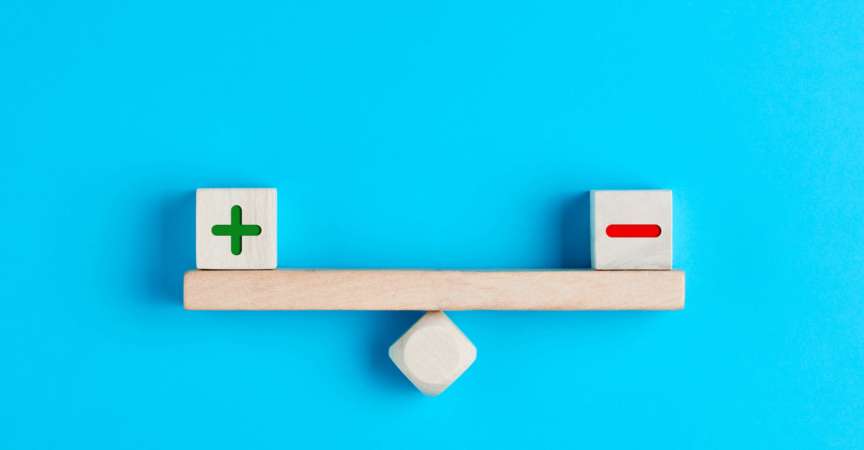 Plus und Minus oder positive und negative Symbole auf Holzklötzen sind auf einer Holzwippe im Gleichgewicht