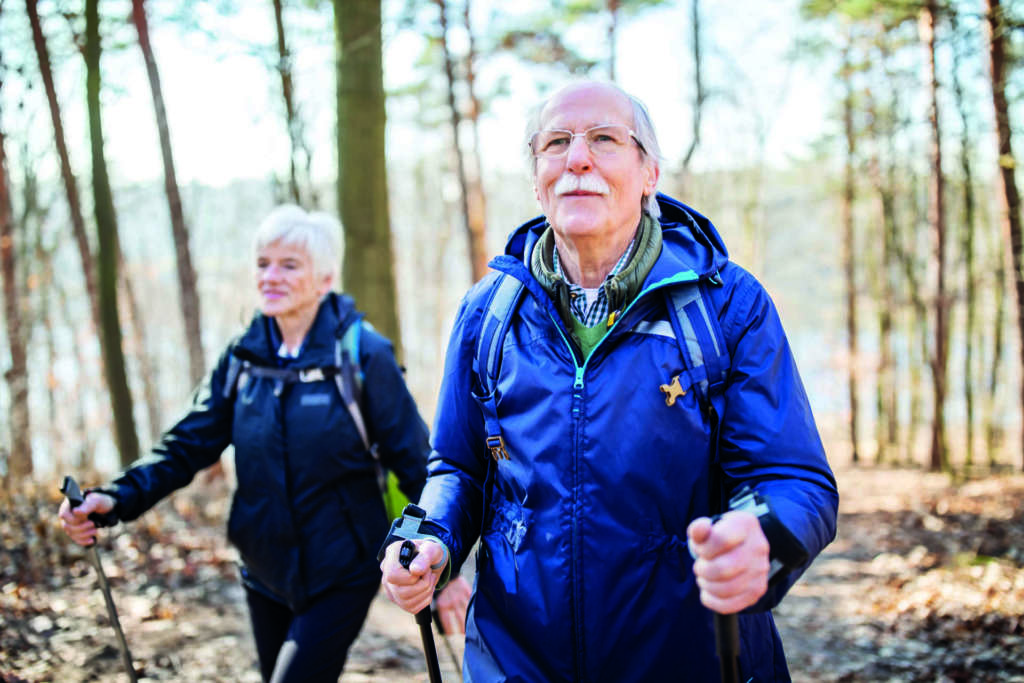 Senioren im Ruhestand, der vorne mit einer Frau auf einem Waldweg geht. Ältere Leute auf einem Landspaziergang.