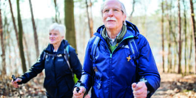 Senioren im Ruhestand, der vorne mit einer Frau auf einem Waldweg geht. Ältere Leute auf einem Landspaziergang.