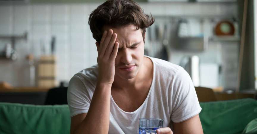 Junger Mann, der zu Hause an Kopfschmerzen, Migräne oder Kater leidet