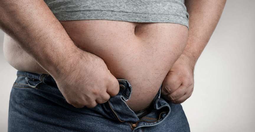 Fettleibigkeitskonzept, Nahaufnahme eines übergewichtigen Mannes, der versucht, zu kleine Jeans mit Kopierraum zu tragen