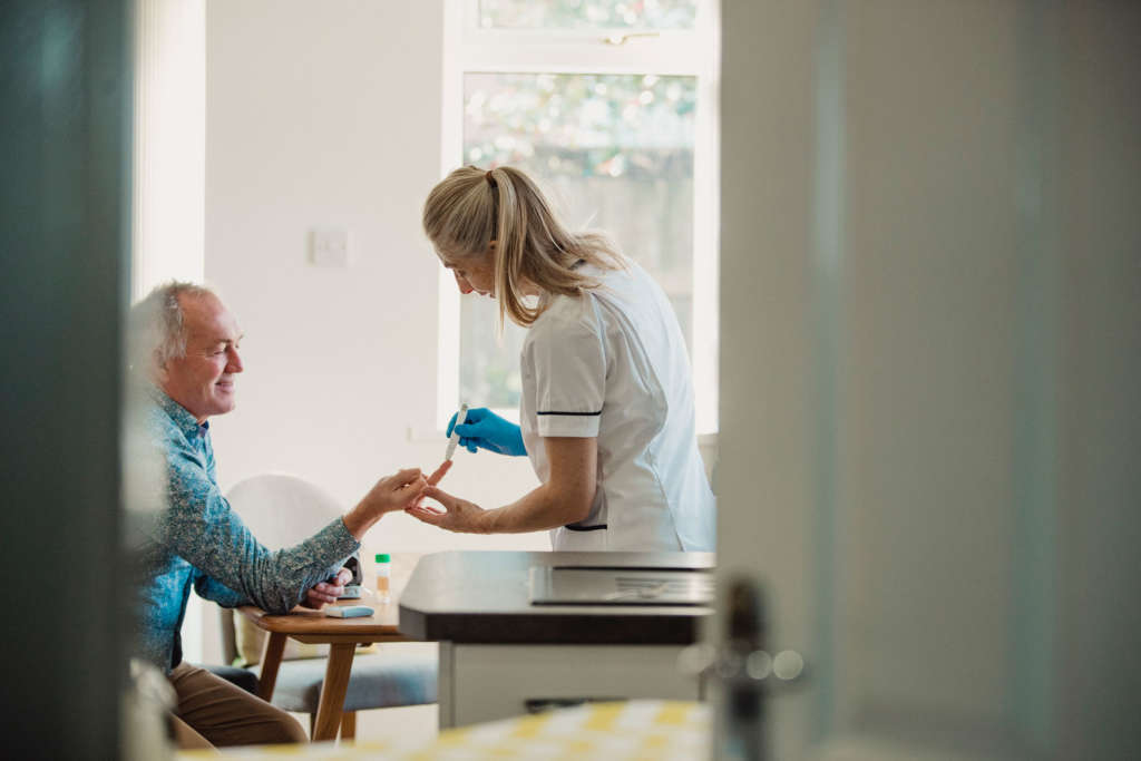 Krankenschwester prüft Diabetes Werte bei einem älteren Mann
