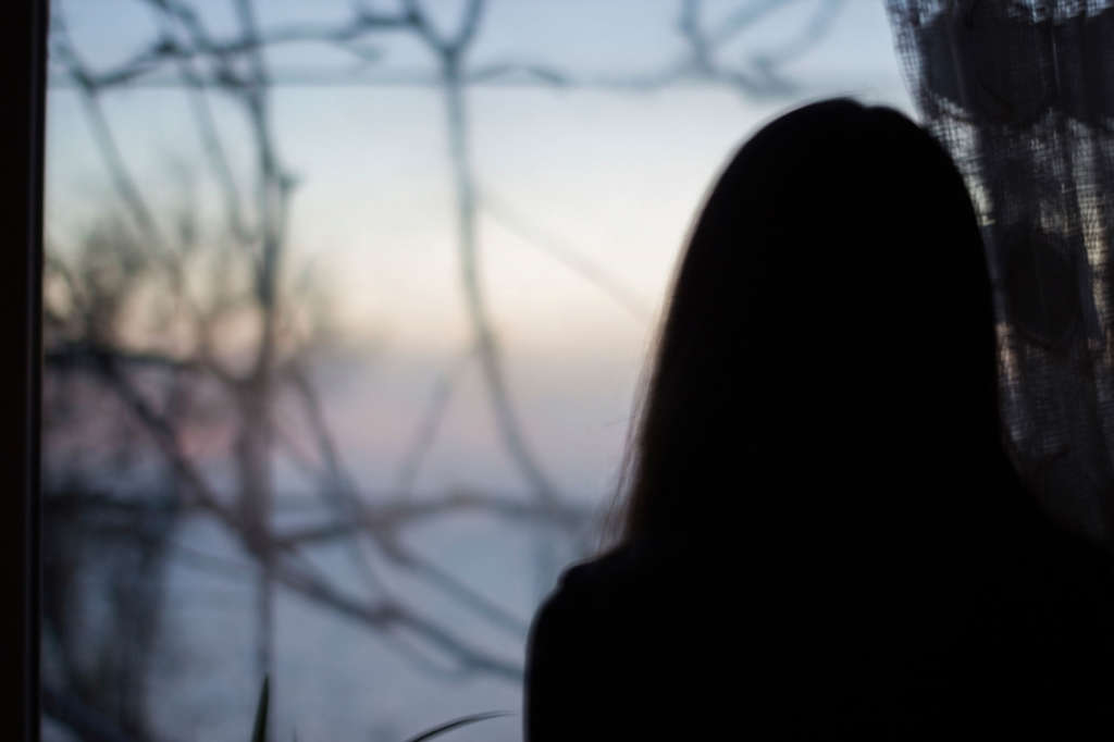 Silhouette eines Mädchen am dunklen Fenster-im-haus