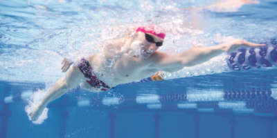 Underwated photo of a young muscular man swimming front crawl style through the olympic swimming pool.