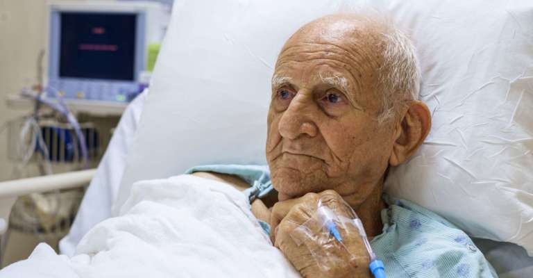 Älterer über 80-jähriger Mann, der sich von einer Operation in einem Krankenhausbett erholt.