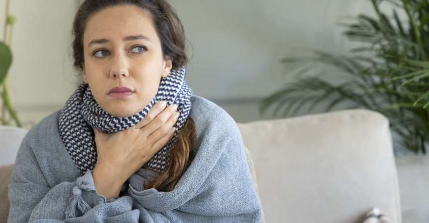 Junge Frau berührt schmerzhaften Hals, Halsschmerzen bei Grippe, Erkältung und Infektion
