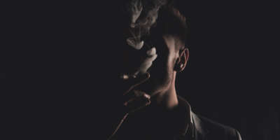 Mystery man with cigar and smoke isolated on black background