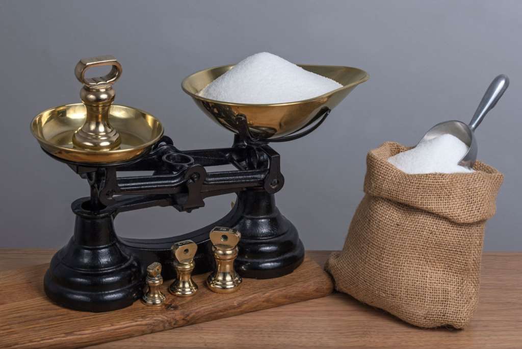 Verwendung einer antiken Waage aus Gusseisen zum Wiegen von Zucker