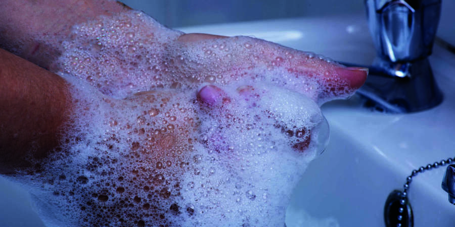 Eine Person wäscht die Hände mit Seife in einem Becken