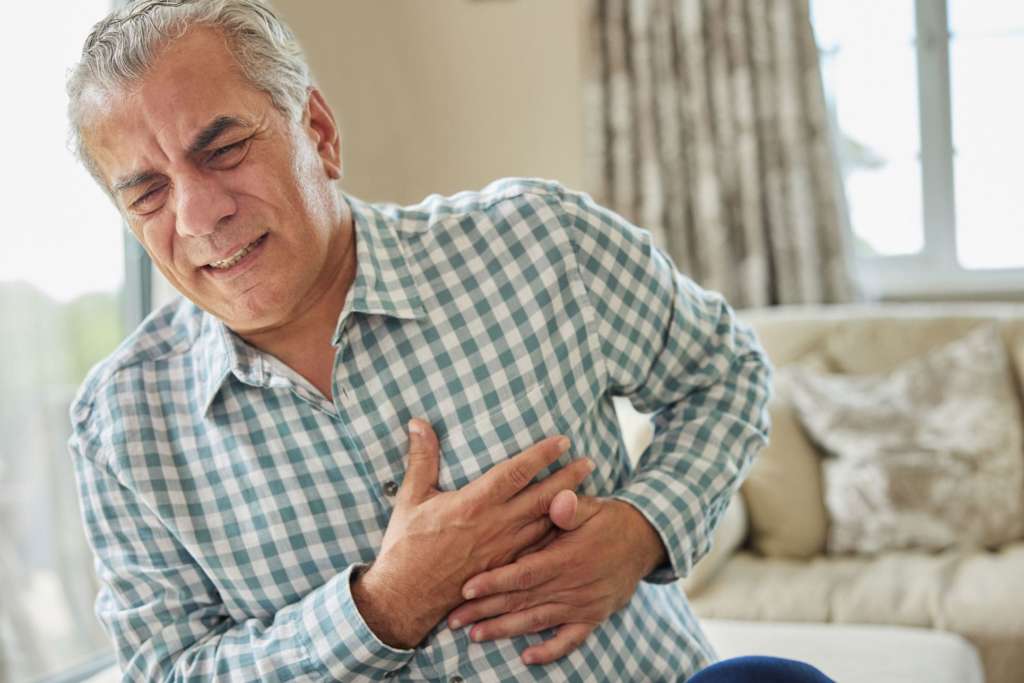 Älterer Mann hebt sich an der Brust weil er Herzschmerzen hat