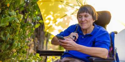 Frau mit einer körperlichen Behinderung durch Multiple Sklerose sitzt im Rollstuhl
