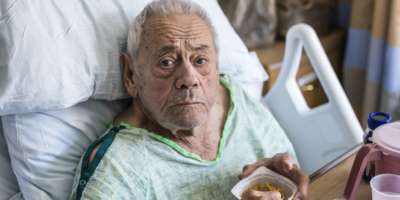 Älterer Mann-Krankenhaus-Patient, der Frühstücksflocken mit Portionskontrolle isst
