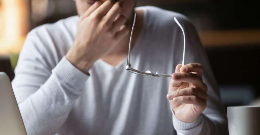 Müde von Computergeschäftsmann, der die Brille abnimmt, fühlt er sich überanstrengt