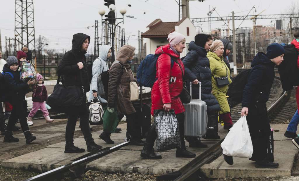 Lemberg, Ukraine - 3. März 2022: Nachdem sie gerade einen Zug verlassen haben, gehen die Menschen mit ihrem Gepäck über die Gleise in Lemberg.