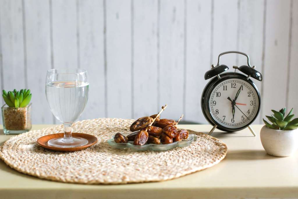 Glas Wasser und Datteln mit Wecker, der 6 Uhr zeigt. Traditioneller Ramadan, Iftar-Zeitkonzept