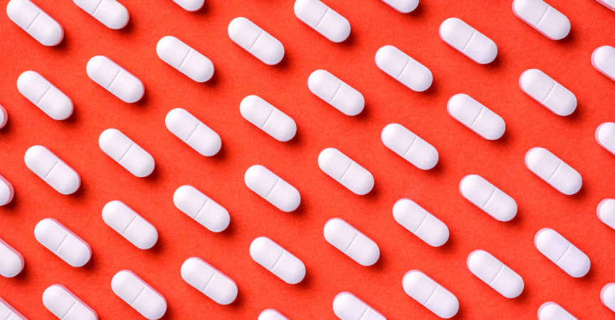 Orange und roter Medizinhintergrund mit weißen Pillen und Tablette, Makro.