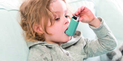 Kleines Kind, das sein Inhalationsgerät für Asthma verwendet