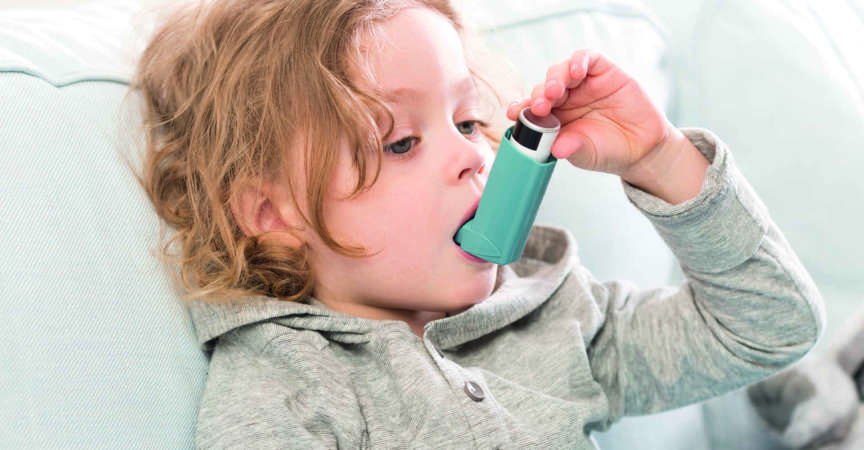 Kleines Kind, das sein Inhalationsgerät für Asthma verwendet