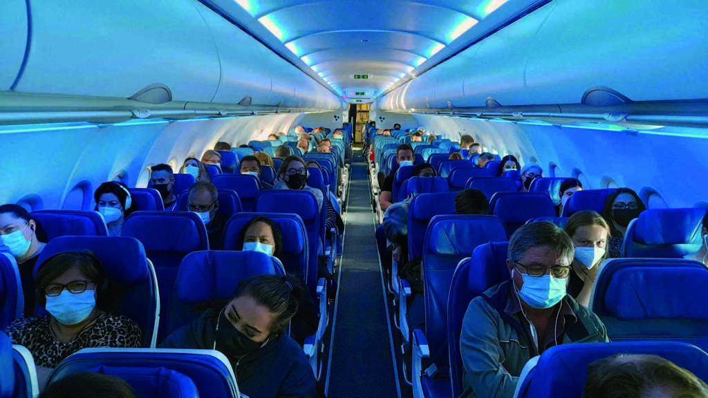 Menschen, die aufgrund von COVID-19 eine Gesichtsmaske tragen, sitzen im Flugzeug, Kanada