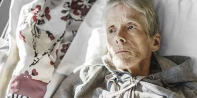 Eine kranke, ältere Seniorin in einem Krankenhausbett