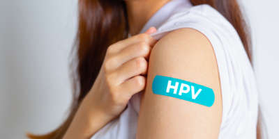 HPV (Humanes Papillomavirus) Teenager-Frau, die einen blauen Verband zeigt, nachdem sie den HPV-Impfstoff erhalten hat. Viren Einige Stämme infizieren Genitalien und können Gebärmutterhalskrebs verursachen. Frauengesundheitskonzept.