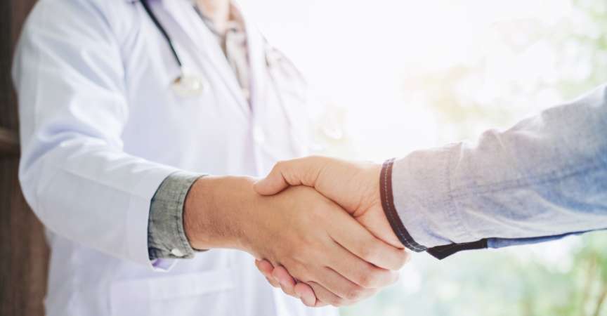 Selbstbewusster Arzt, der Patienten im Krankenhaus die Hände schüttelt