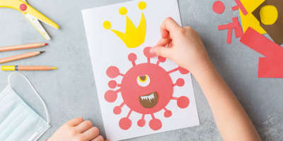 Blatt von oben auf einem Tisch mit Kinderhänden, die eine Viruszelle zeichnen