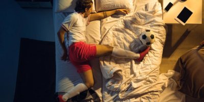 Kind mit Fussball Kleider auf dem Bett