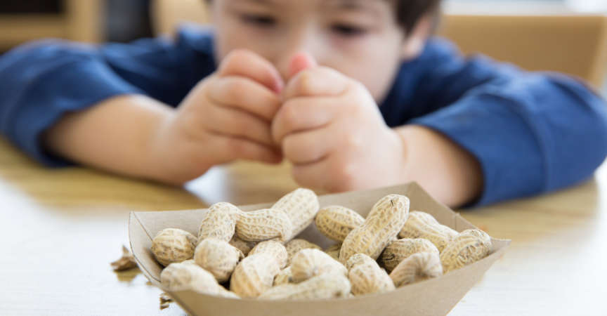 Little boy opening up peanuts to eat in a restaurant