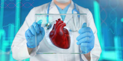 Nicht erkennbarer Arzt im Mittelgrund hält ein durchsichtiges Tablet in die Kamera, mit einer 3D-Illustration eines Herzens