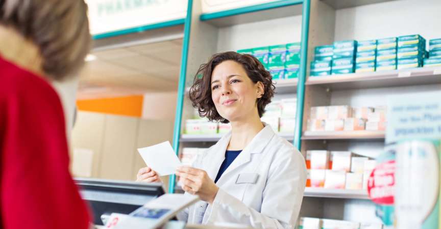 Glückliche Apothekerin, die Frauen beim Kauf von Medikamenten in der Apotheke hilft