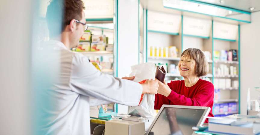Männlicher Apotheker gibt älteren Kunden in einer Apotheke verschreibungspflichtige Medikamente