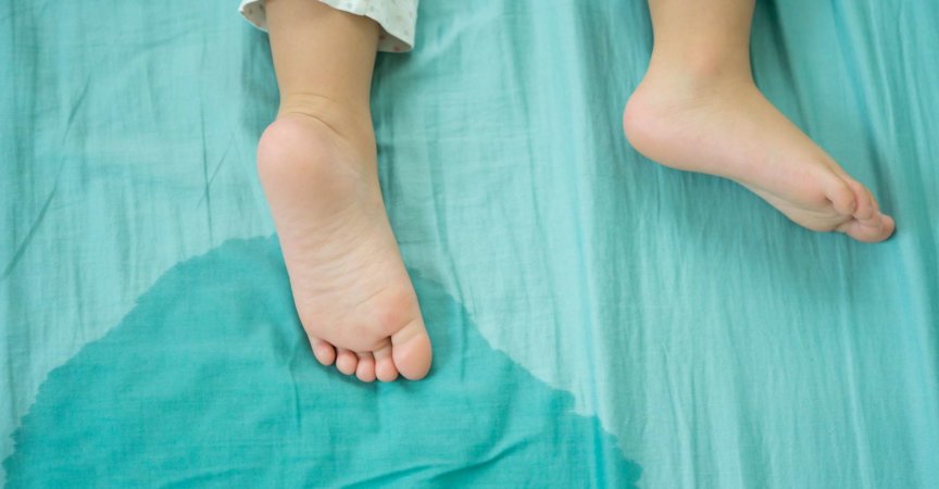 Kinderfüße und pinkeln in einer Matratze.kleine Mädchenfüße und pinkeln am Morgen in Bettlaken.Entwicklungskonzept für Kinder.