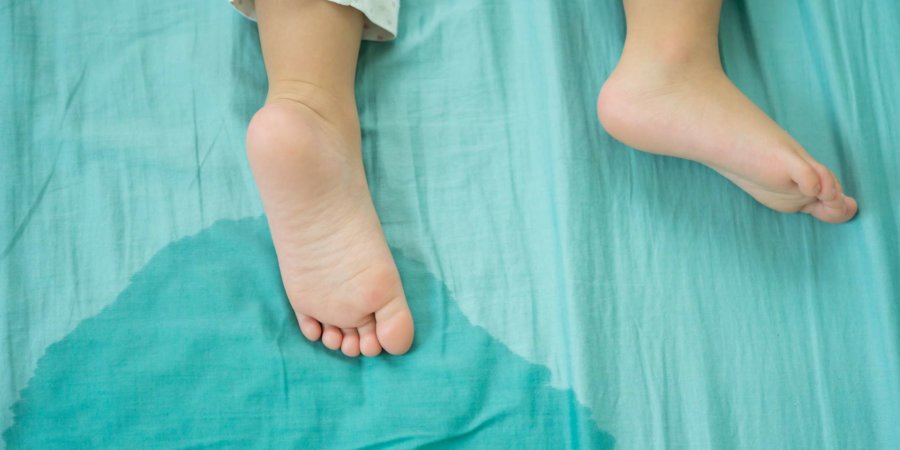 Kinderfüße und pinkeln in einer Matratze.kleine Mädchenfüße und pinkeln am Morgen in Bettlaken.Entwicklungskonzept für Kinder.