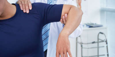 Arzt untersucht Schulter eines männlichen Patienten