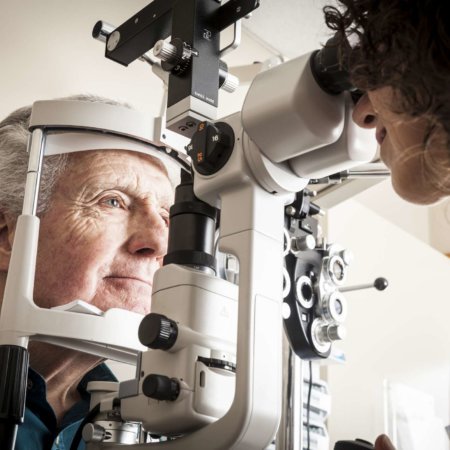 Optiker, der älteren Patienten eine Augenuntersuchung gibt