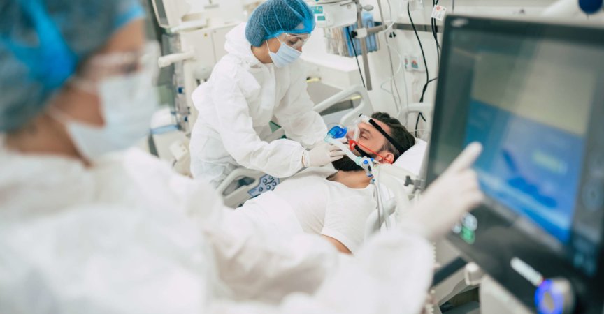 Coronavirus covid-19 infizierter Patient in einer Quarantänestation im Krankenhaus mit Ärzten in Schutzanzügen, während sie ihn behandeln